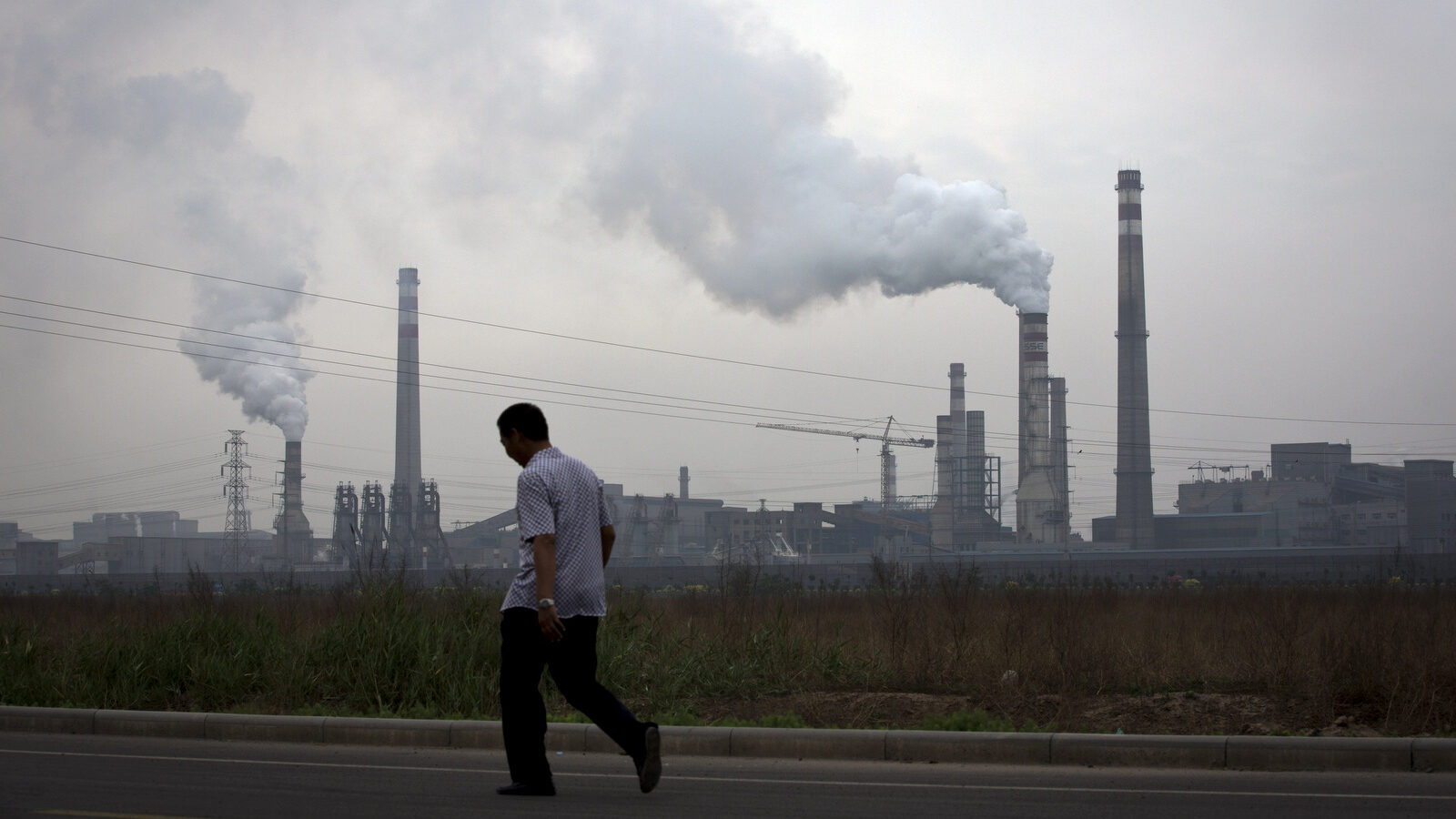A man walks past a coal-powered steel plant in Tianjin, China. (AP/Andy Wong)