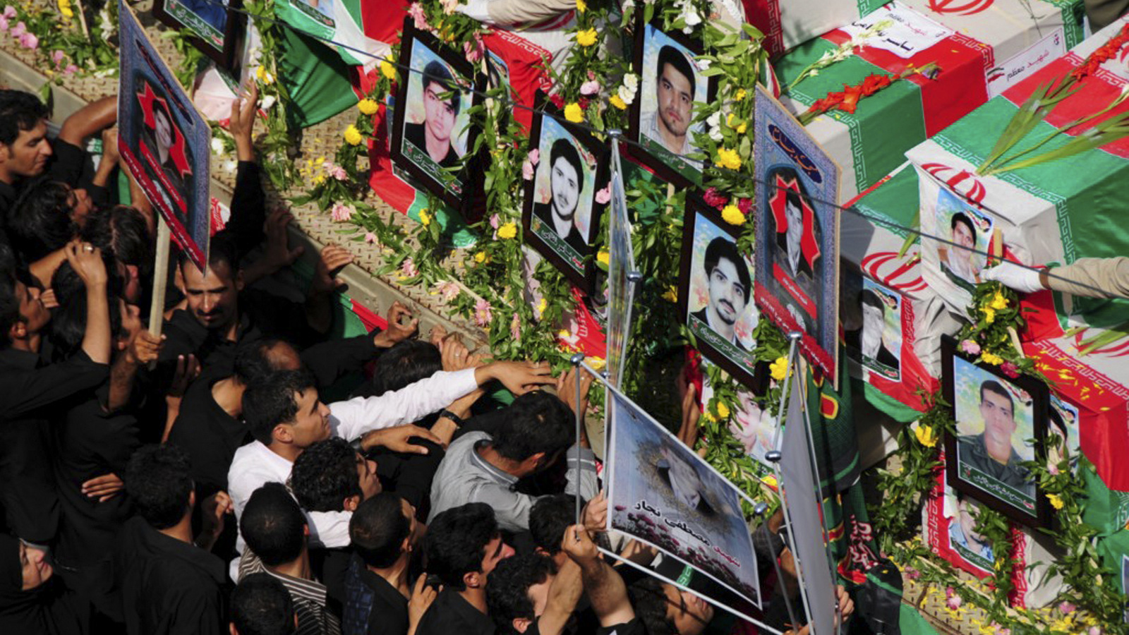 Lors d'une cérémonie funéraire, des gens pleurent à côté des cercueils drapés de drapeaux des victimes de deux attentats à la bombe dans la ville de Zahedan, en Iran, le 17 juillet 2010. Jundallah, qui a perpétré plusieurs autres attentats à la bombe dans le sud-est de l'Iran au cours des dernières années, a revendiqué la responsabilité des explosions, qui ont fait 27 morts. (Fars/Ali Azimzadeh)