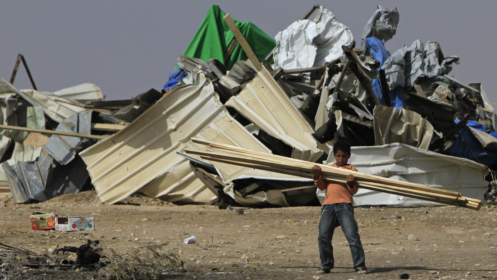 Un niño beduino transporta madera después de demoler su casa en la aldea de El Araqib, cerca de la ciudad de Beersheba, en el sur de Israel, en 2010. (AP / Tsafrir Abayov)