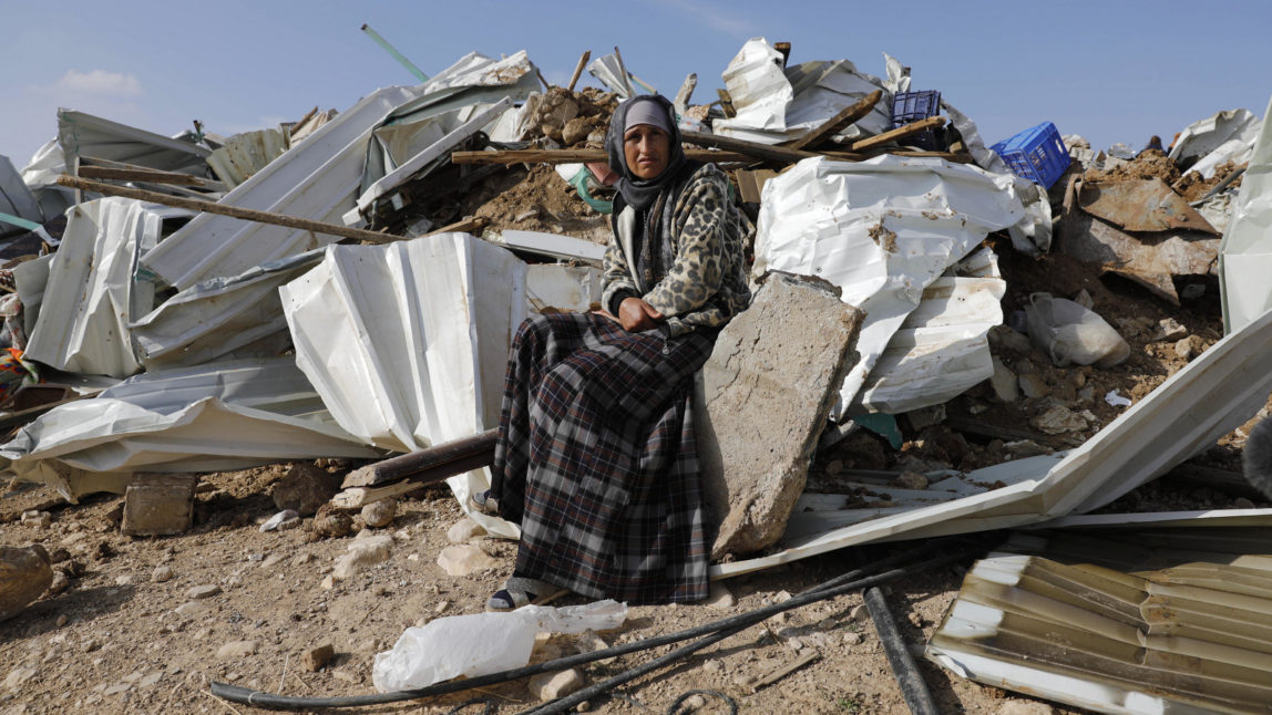A Bedouin woman sit on the remnants of her demolished home in the Bedouin village of Umm al-Hiran, near the southern city of Beersheba, Israel, Jan. 18, 2017. (AP/Tsafrir Abayov)