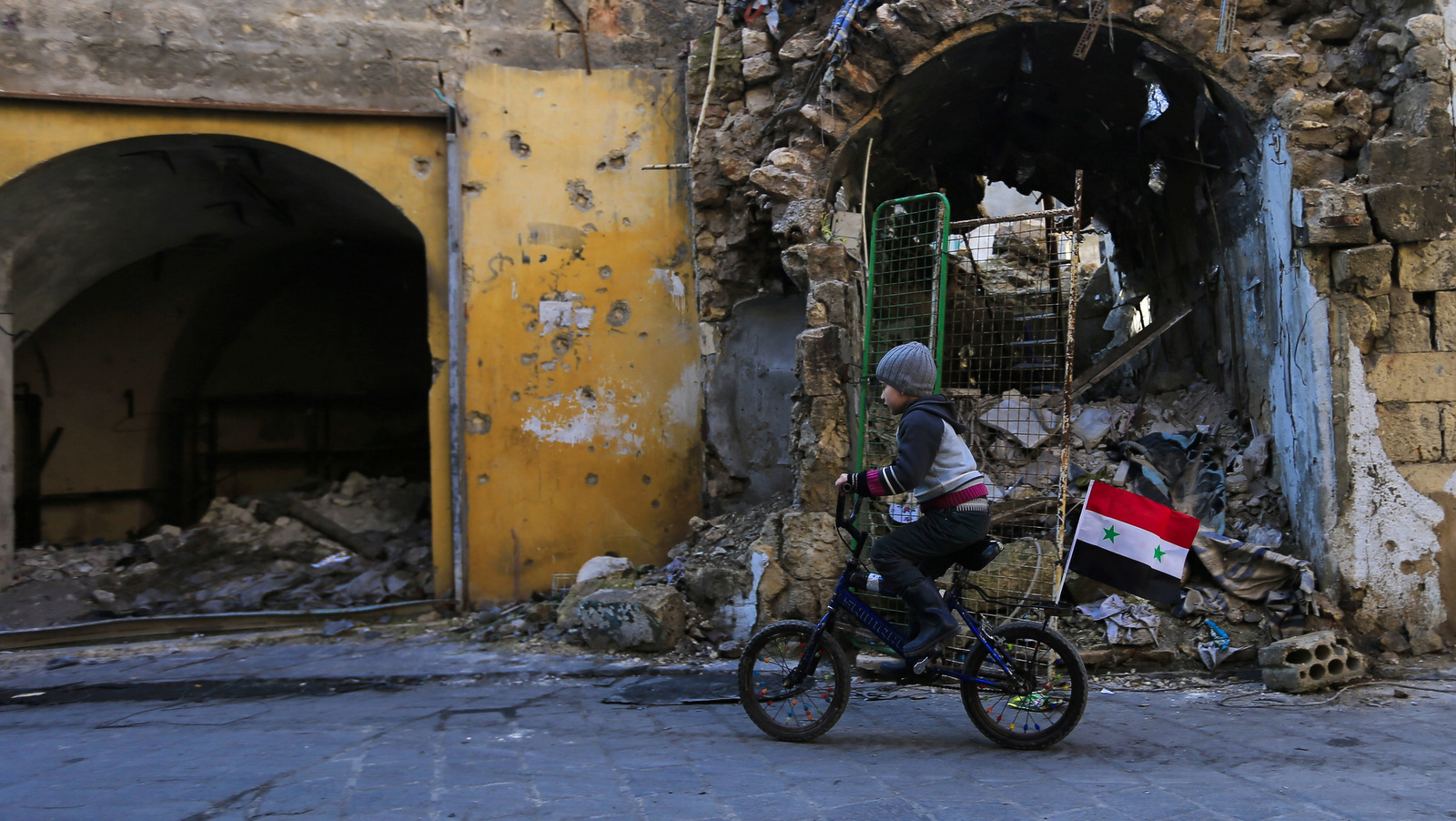 A young boy rides his bike through the destruction of the once Jalloum neighborhood in the eastern Aleppo, Syria after it was liberated from Syrian rebels, Jan. 20, 2017. (AP/Hassan Ammar)
