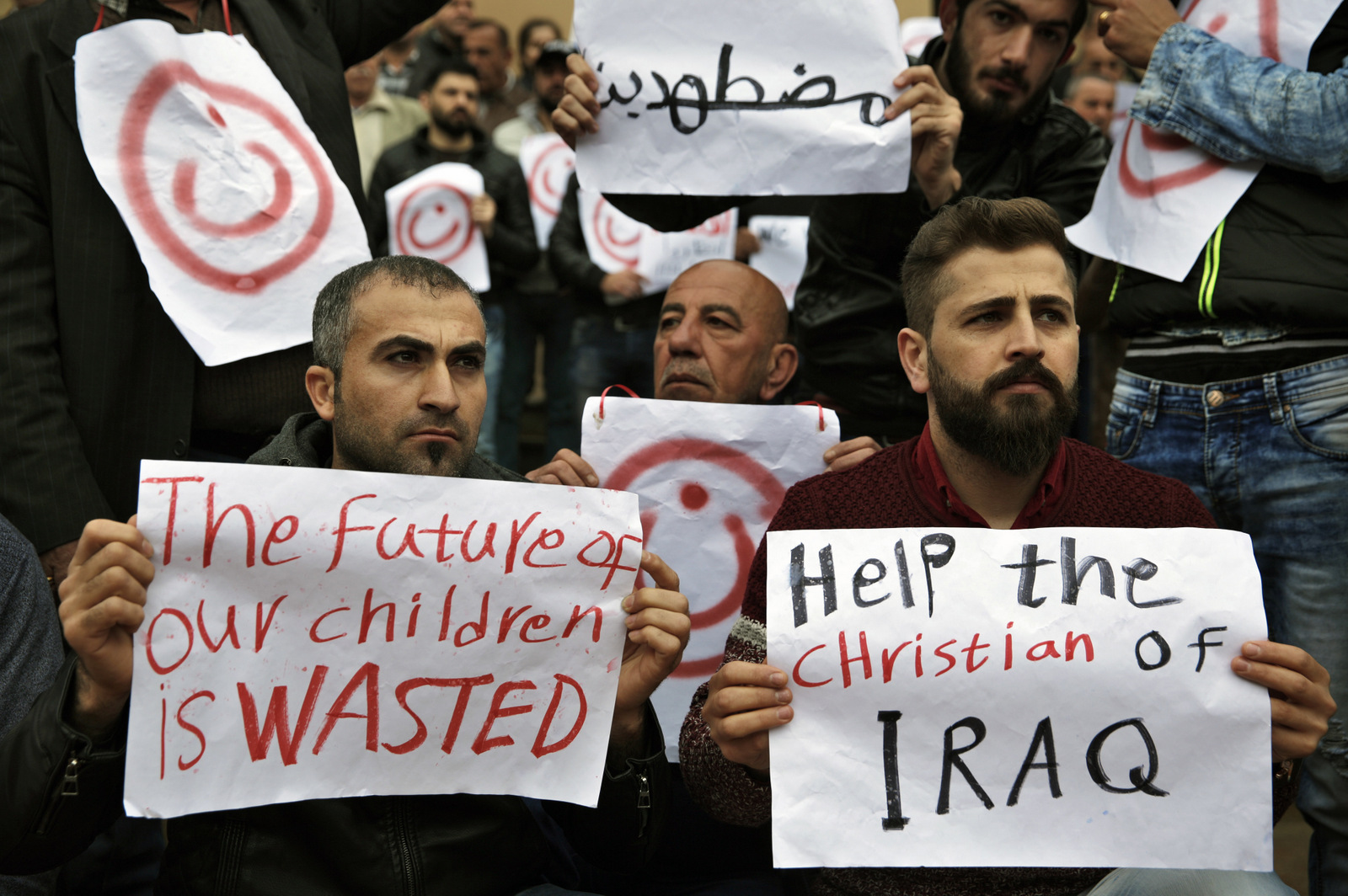 Iraqi Christians who live in Lebanon hold placards during a sit-in, in front of the United Nations Headquarters demanding speeding up their immigration cases in Beirut, Lebanon, Feb. 13, 2017. Thousands of Christians from Iraq and Syria have fled violence in their country and sought refuge in Lebanon, a religiously-mixed country. The placard in Arabic reads "Oppressed." (AP/Bilal Hussein)