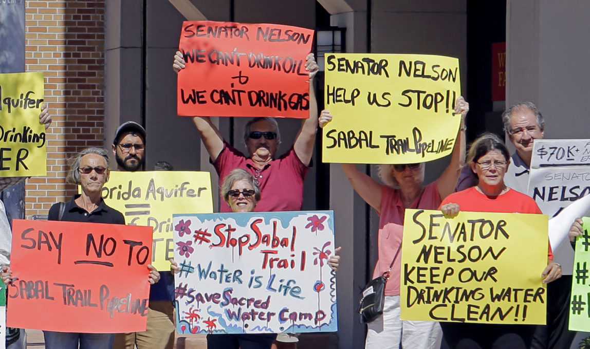 Activists hold signs as they protest the Sabal Trail pipeline, in front of the office of U.S. Sen. Bill Nelson, Tuesday, Feb. 14, 2017, in Coral Gables, Fla. The Sabal Trail is an underground natural gas pipeline project that originates in Alabama, stretches through Georgia and terminates in Florida. (AP/Alan Diaz)