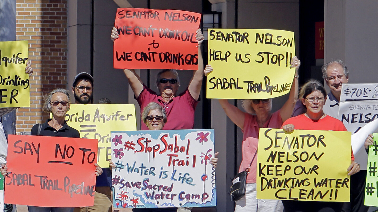 Activists hold signs as they protest the Sabal Trail pipeline, in front of the office of U.S. Sen. Bill Nelson, Tuesday, Feb. 14, 2017, in Coral Gables, Fla. The Sabal Trail is an underground natural gas pipeline project that originates in Alabama, stretches through Georgia and terminates in Florida. (AP/Alan Diaz)