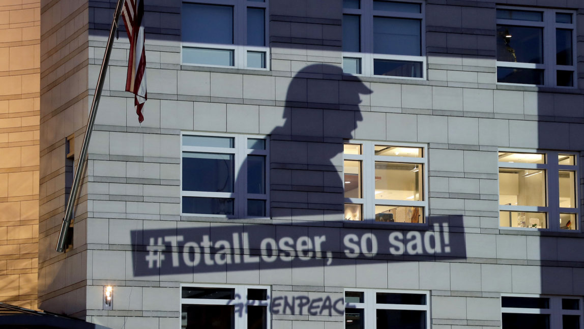 A Greenpeace banner showing U.S. President Donald Trump and the slogan '#TotalLoser, so sad!' is projected onto the facade of the U.S. Embassy in Berlin, Germany, Friday, June 2, 2017. (AP/Michael Sohn)