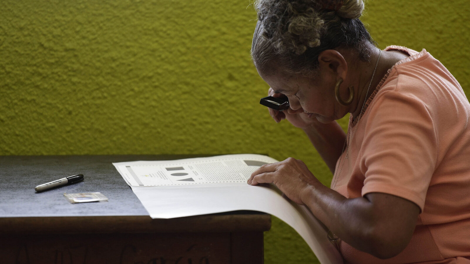 Puerto Rican resident Maria Quinones looks carefully at her ballot with a magnifying glass before voting during the fifth referendum on the island's status, in San Juan, Puerto Rico, June 11, 2017. (AP/Carlos Giusti)