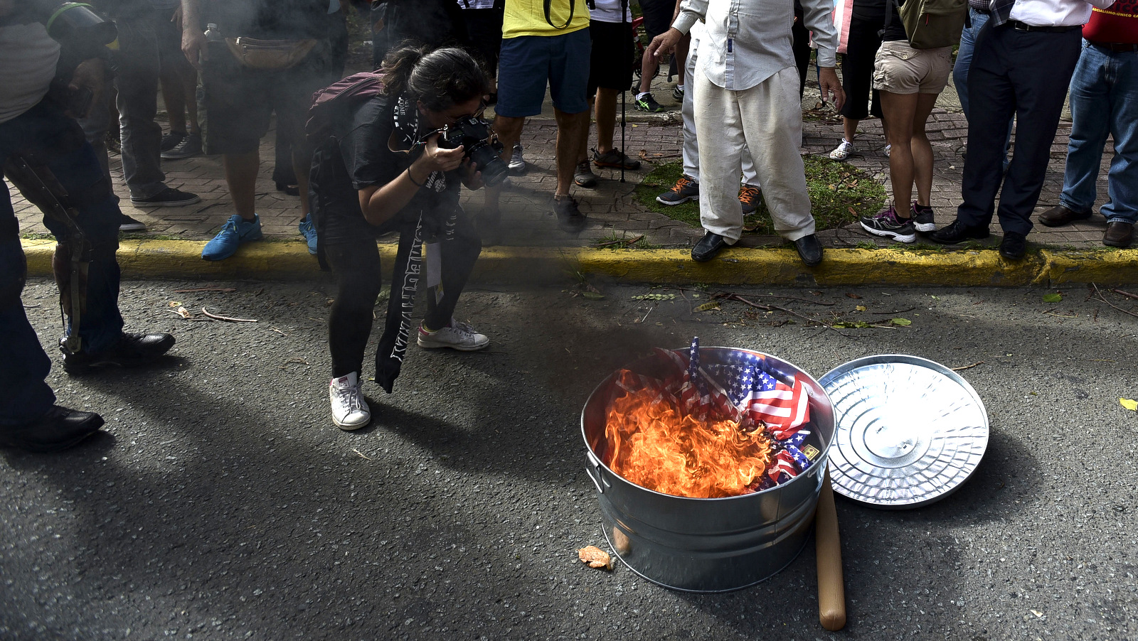 A woman photographs a burning U.S. flag set on fire during protesters in favor of Puerto Rico's independence after a referendum was held on the island's status in the financial district, known as the golden mile, in San Juan, Puerto Rico, Sunday, June 11, 2017. The U.S. territory overwhelmingly chose statehood on Sunday in a non-binding referendum held amid a deep economic crisis that has sparked an exodus of islanders to the U.S. mainland. Voter turnout was just 23 percent. (AP/Carlos Giusti)