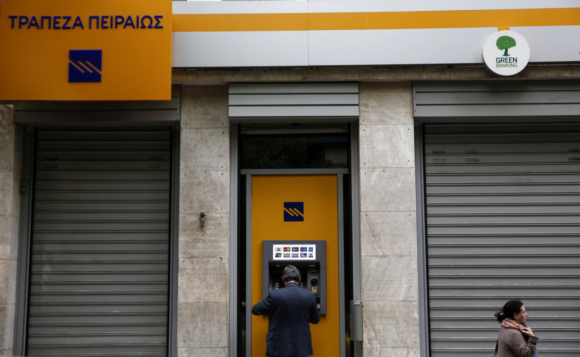 A man makes a transaction at an automated teller machine (ATM) of a Piraeus Bank branch in Athens, Greece. (AP/Yorgos Karahalis)