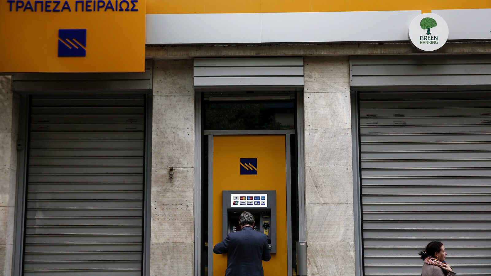 A man makes a transaction at an automated teller machine (ATM) of a Piraeus Bank branch in Athens, Greece. (AP/Yorgos Karahalis)