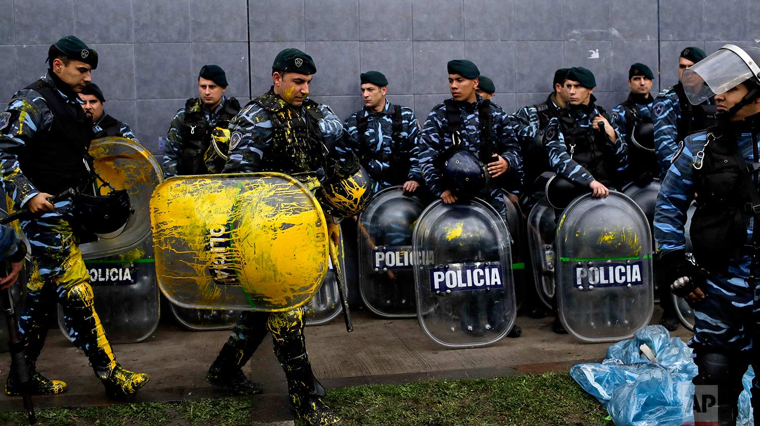 Police who were stained with yellow paint thrown by protesters, form outside the PepsiCo plant on the outskirts of Buenos Aires, Argentina, Thursday, July 13, 2017. Security forces clashed Thursday with former PepsiCo employees after resisting eviction from the plant. Workers had occupied the plant after PepsiCo closed the plant last month.(AP/Natacha Pisarenko)