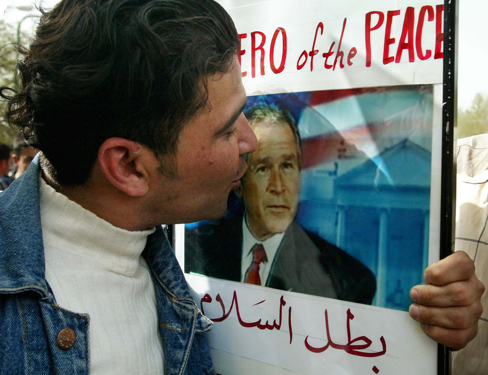 A Kurd kisses a picture of United States President George W. Bush during celebrations in the streets of Sulaymaniyah, northern Iraq Wednesday April 9, 2003. (AP/Kevin Frayer)