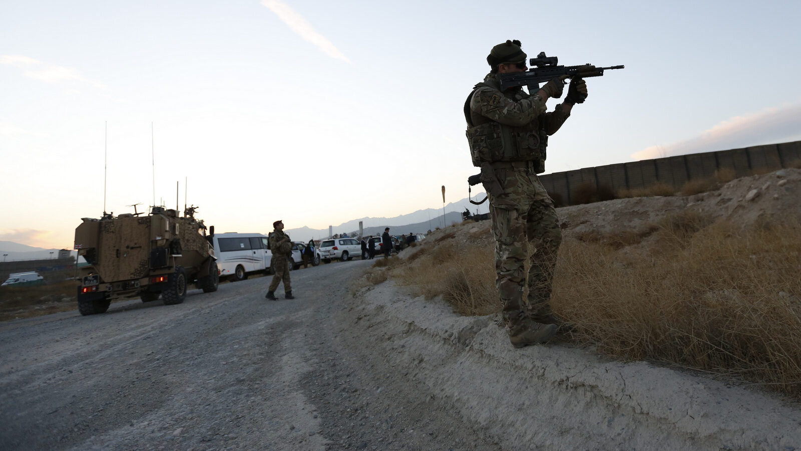 A British soldier looks through the scope of a machine gun to observe an area as he waits for the arrival of Britain's Foreign Secretary Boris Johnson during his visit to Camp Qargha in Kabul, Afghanistan, Nov. 26, 2016. (Mohammad Ismail/AP)