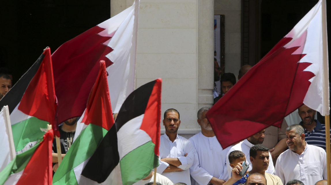 Residents of Qatari-funded housing complex wave their national and Qatari flags during demonstration in solidarity with Qatar in front of Sheikh Hamad bin Khalifa al-Thani's mosque in the central of the housing complex in Khan Younis, Gaza Strip, June 9, 2017. (AP/Adel Hana)