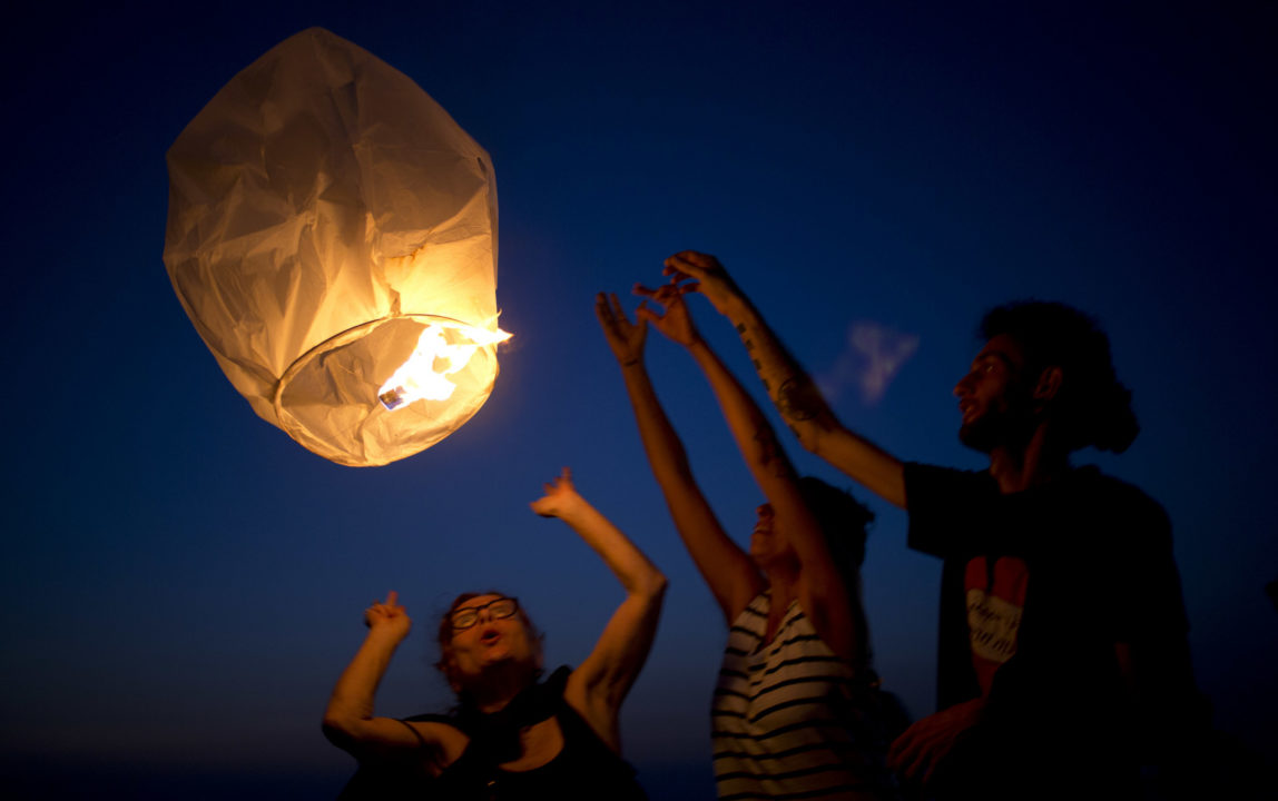 Activists release paper lanterns in solidarity with Palestinians from Gaza, at the Ashkelon beachafter Israel cut back its already limited electricity shipments to the Gaza Strip in a step that is expected to worsen the power crunch plaguing the Hamas-controlled seaside territory, June 19, 2017. (AP/Ariel Schalit)