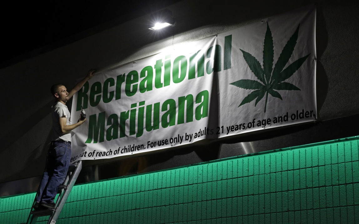 Bryce Tallitsch hangs up a sign for recreational marijuana at the NuLeaf dispensary, June 30, 2017, in Las Vegas. Nevada dispensaries were legally allowed to sell recreational marijuana starting at 12:01 a.m. Saturday. (AP/John Locher)