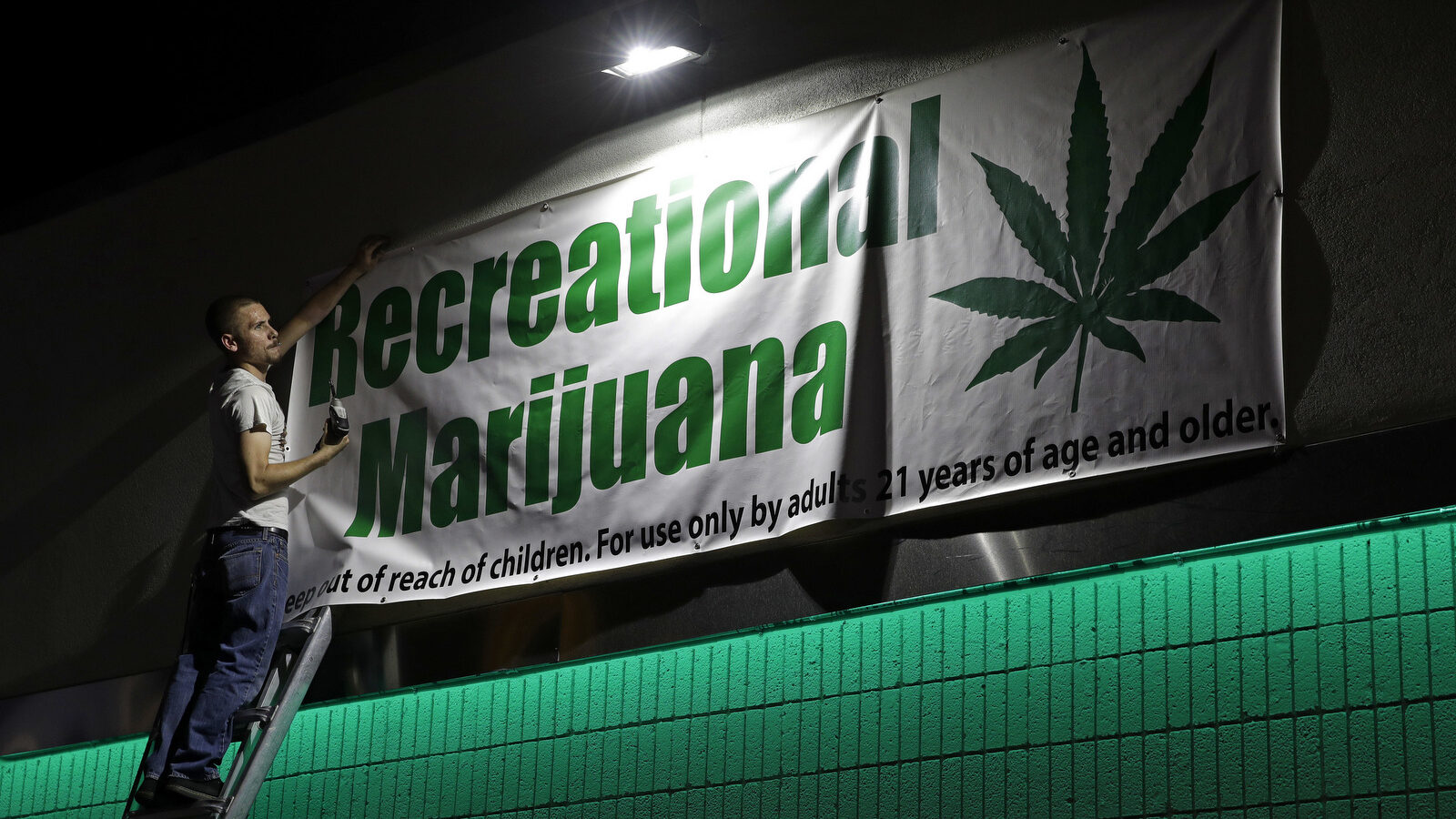 Bryce Tallitsch hangs up a sign for recreational marijuana at the NuLeaf dispensary, June 30, 2017, in Las Vegas. Nevada dispensaries were legally allowed to sell recreational marijuana starting at 12:01 a.m. Saturday. (AP/John Locher)