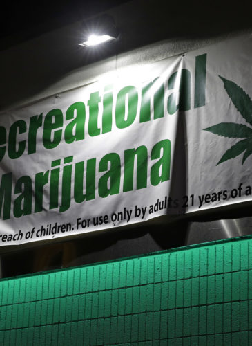 Bryce Tallitsch hangs up a sign for recreational marijuana at the NuLeaf dispensary, June 30, 2017, in Las Vegas. Nevada dispensaries were legally allowed to sell recreational marijuana starting at 12:01 a.m. Saturday. (AP/John Locher)