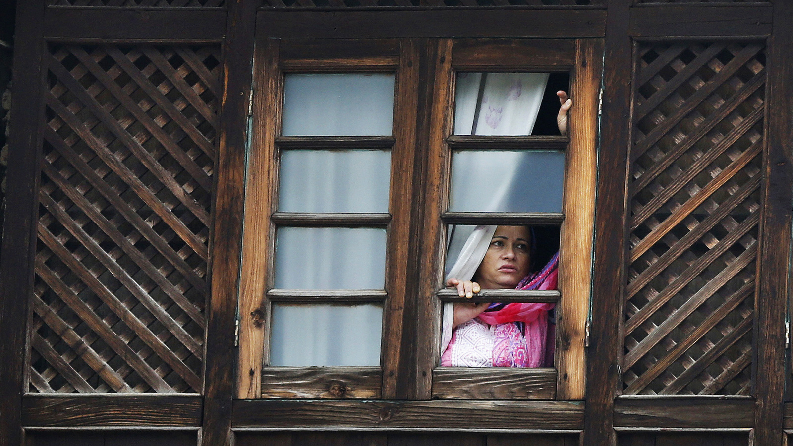 A Kashmiri woman watches Martyrs' Day ceremony from the window of her house in Srinagar, Indian controlled Kashmir, July 13, 2017. July 13 is observed as Martyrs' Day in memory of the day when the region s Hindu king ordered more than 20 Kashmiri Muslims executed in a bid to put down an uprising in 1931. (AP/Mukhtar Khan)