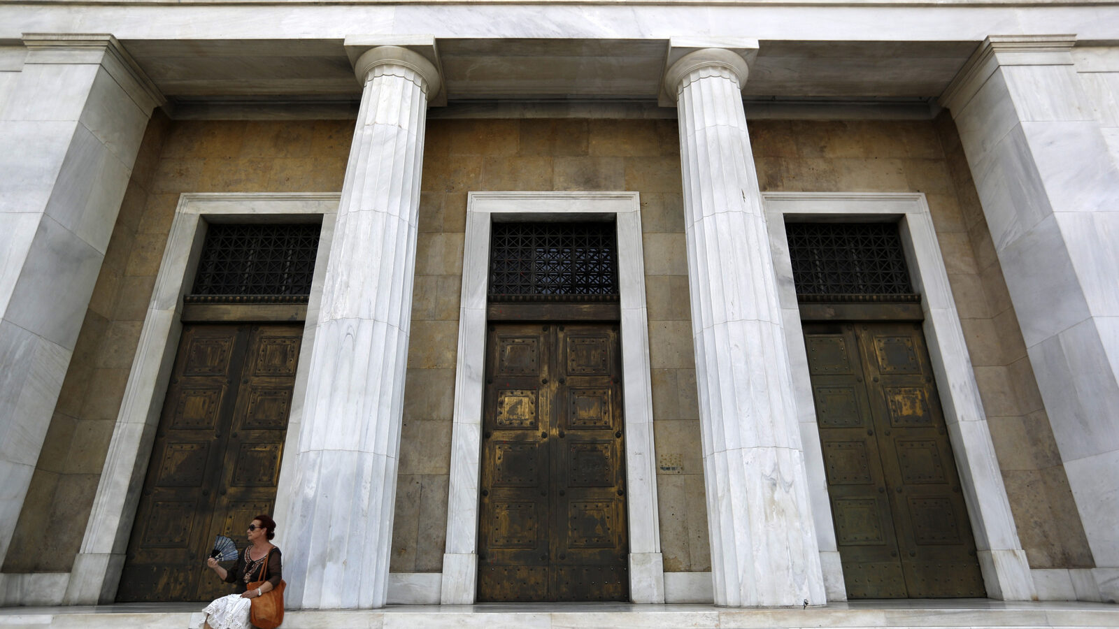 A woman uses her fan to cool down outside the Bank of Greece headquarters in Athens, July 24, 2017. (AP/Thanassis Stavrakis)