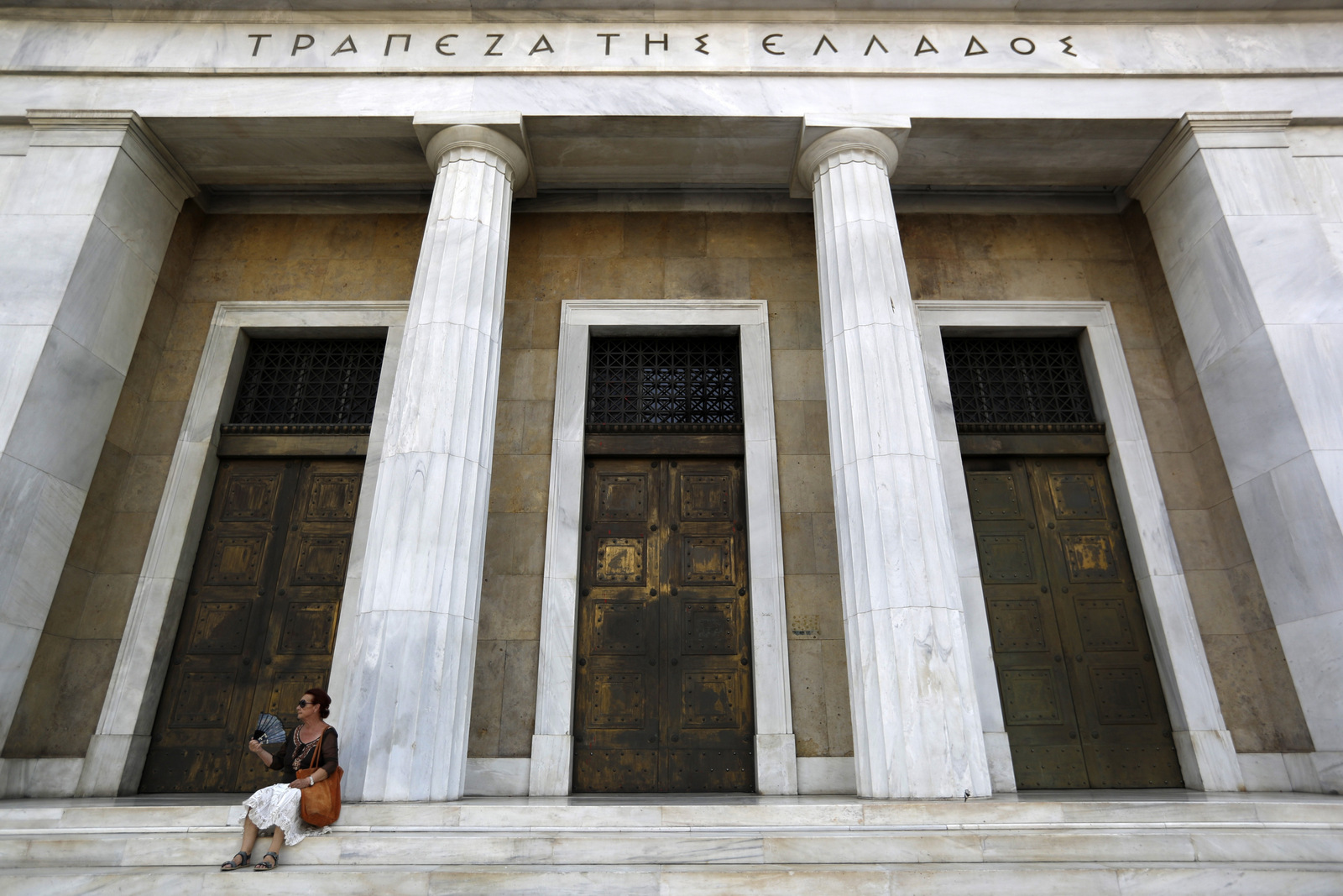 A woman uses her fan to cool down outside the Bank of Greece headquarters in Athens, July 24, 2017. (AP/Thanassis Stavrakis)