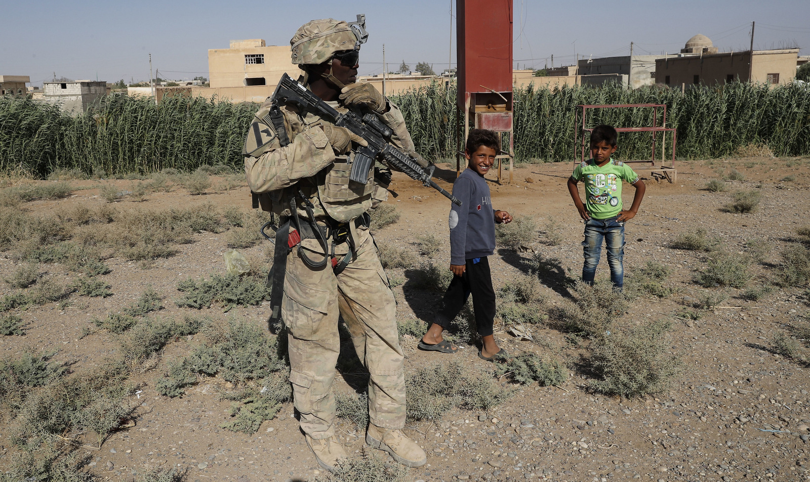 A U.S. soldier stands near Syrian children on a road that links to Raqqa, Syria, July 26, 2017. The U.S. has at least 1,000 troops in Syria. (AP/Hussein Malla)