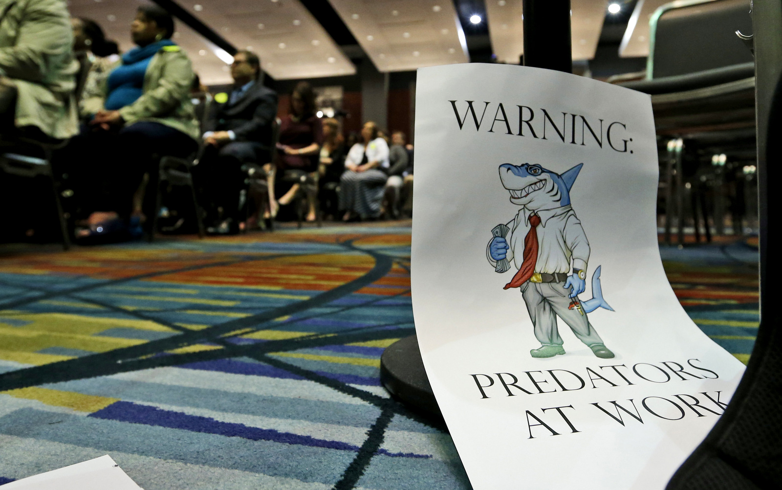 A sign leans against a chair during a speech by Consumer Financial Protection Bureau Director Richard Cordray, in Richmond, Va., March 26, 2015.  (AP/Steve Helber)