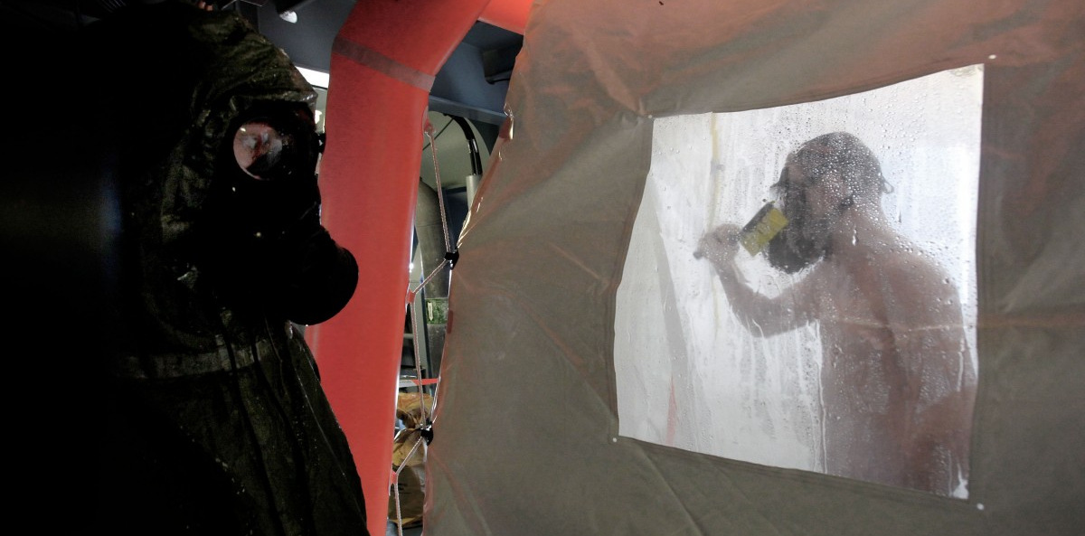 A crew member of the Danish warship Esbern Snare enters a decontamination shower wearing a gas mask, during preparations to head to the Syrian port of Latakia to pick up more than 1,000 tons of chemical agents slated for destruction as agreed upon with the Syrian government. (AP/Petros Karadjias)