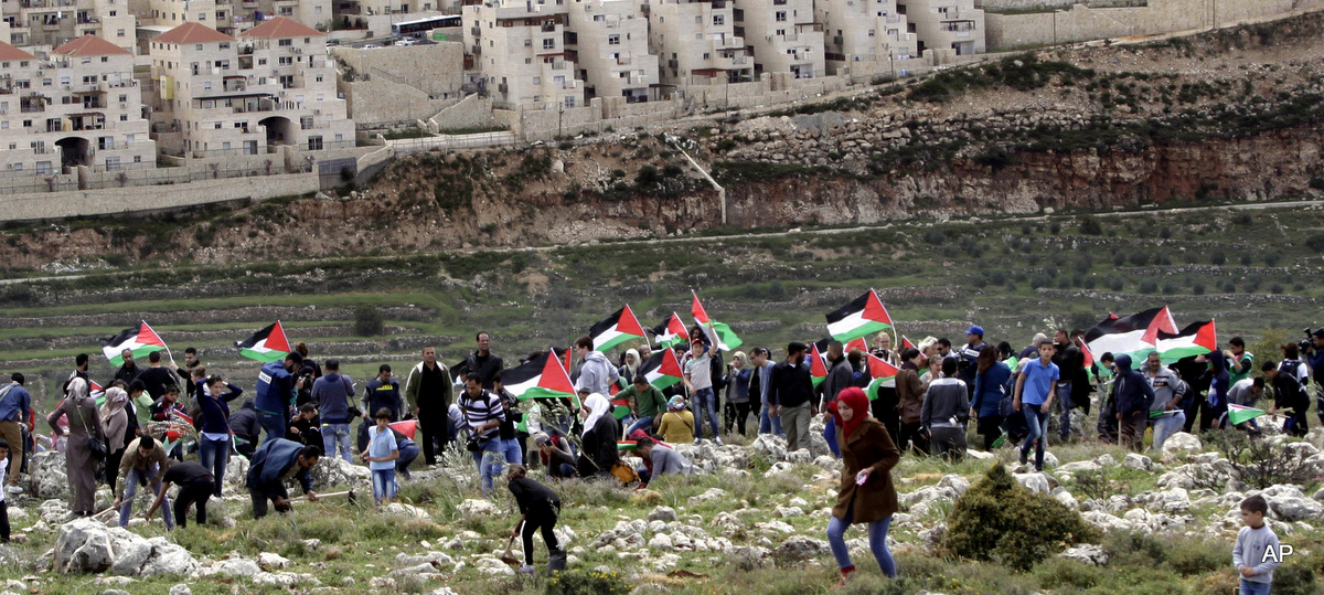 Los manifestantes palestinos portan banderas nacionales y plantan olivos frente al asentamiento israelí de Beitar Illit durante una protesta que conmemora el Día de la Tierra, en el pueblo de Wadi Fukin, cerca de la ciudad de Belén, Cisjordania, el 30 de marzo de 2015.