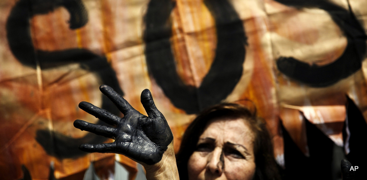 An activist with her hand painted black to symbolize the contamination of oil, takes part in a protest performance demanding measures to prevent oil spills, outside the national oil company in Lima, Peru, Aug. 22, 2016. (AP/Rodrigo Abd)