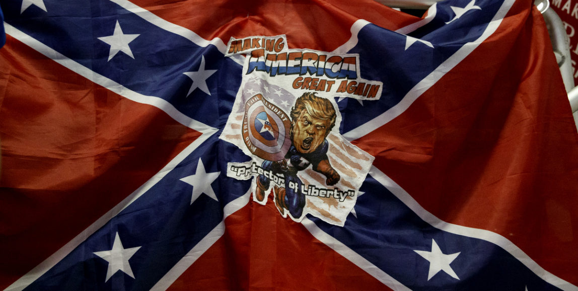A man holds a Confederate flag with a depiction of Republican presidential candidate Donald Trump during a campaign rally at the Jacksonville Equestrian Center, Nov. 3, 2016, in Jacksonville, Fla. (AP/ Evan Vucci)