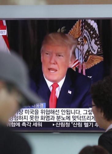 People walk by a TV screen showing a local news program reporting with an image of U.S. President Donald Trump at the Seoul Train Station in Seoul, South Korea, Aug. 9, 2017. (AP/Lee Jin-man)