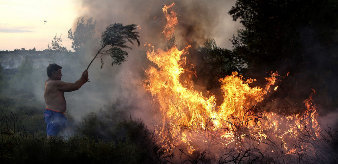 A resident tries to extinguish a forest fire at Kalamos village, north of Athens, on Aug. 13, 2017. A total of 53 wildfires broke out in Greece Saturday and more have done so Sunday, including on the beach resort of Kalamos near Athens. (AP/Yorgos Karahalis)