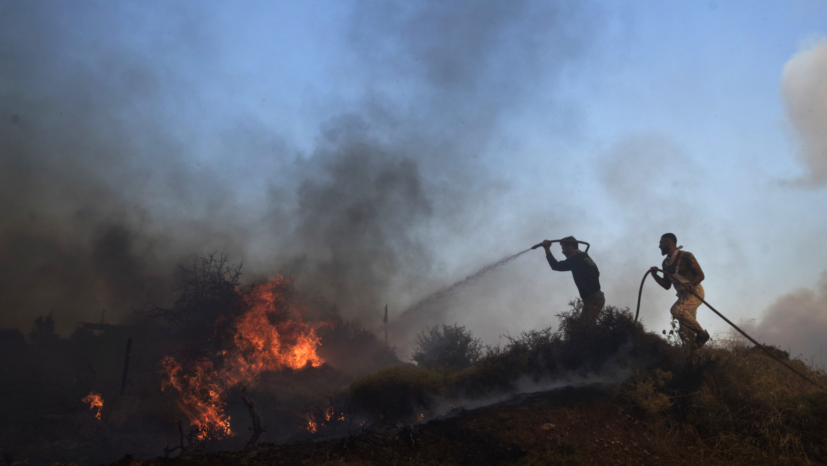 Volunteers try to extinguish the fire outside a military base at the village of Varnava , north of Athens, Aug. 14, 2017. (AP/Petros Giannakouris)