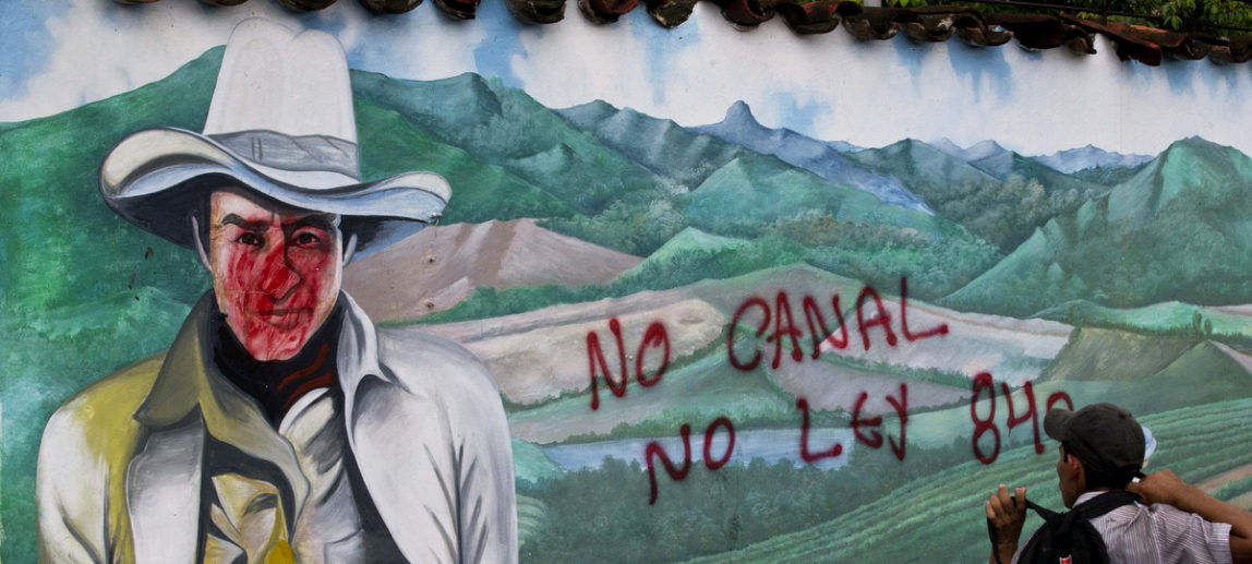 An opponent to Nicaragua's transoceanic canal project walks past a defaced a mural depicting national hero Augusto C. Sandino, in Juigalpa, Nicaragua, June 13, 2015, during a march against the construction of the canal. (AP/Esteban Felix)
