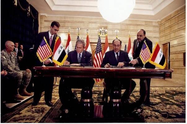 Ali Khedery, en la imagen de la izquierda, observa cómo el presidente de los Estados Unidos, George W. Bush, firma un acuerdo con el primer ministro iraquí, Nouri al-Maliki. (Foto: dominio público)