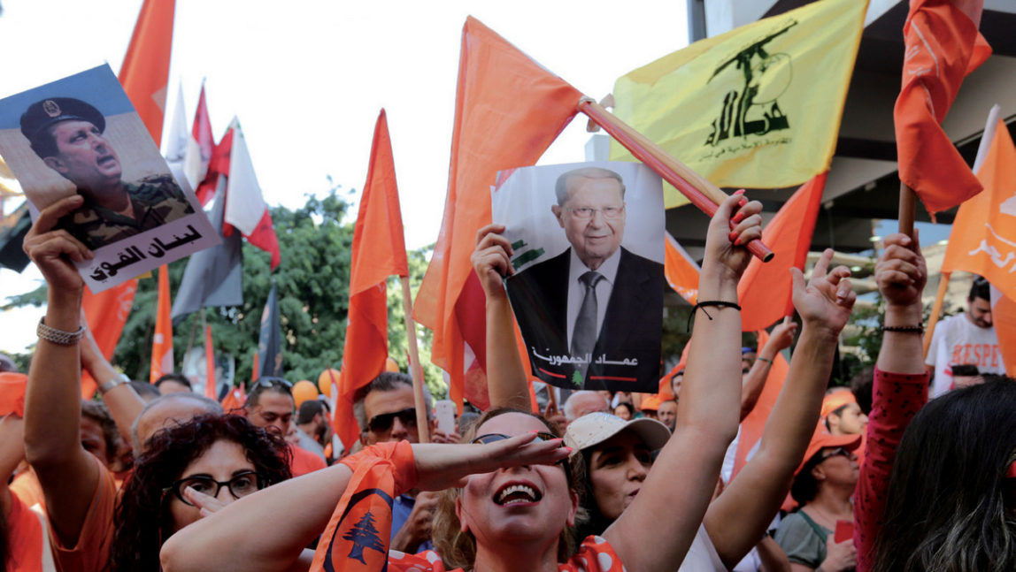 Supporters of Christian leader Michel Aoun hold his picture and Free Patriotic Movement, Lebanese flags and Hezbollah flag as they celebrate the election of President Michel Aoun, in Beirut, Lebanon, Monday, Oct. 31, 2016. (AP/Hassan Ammar)