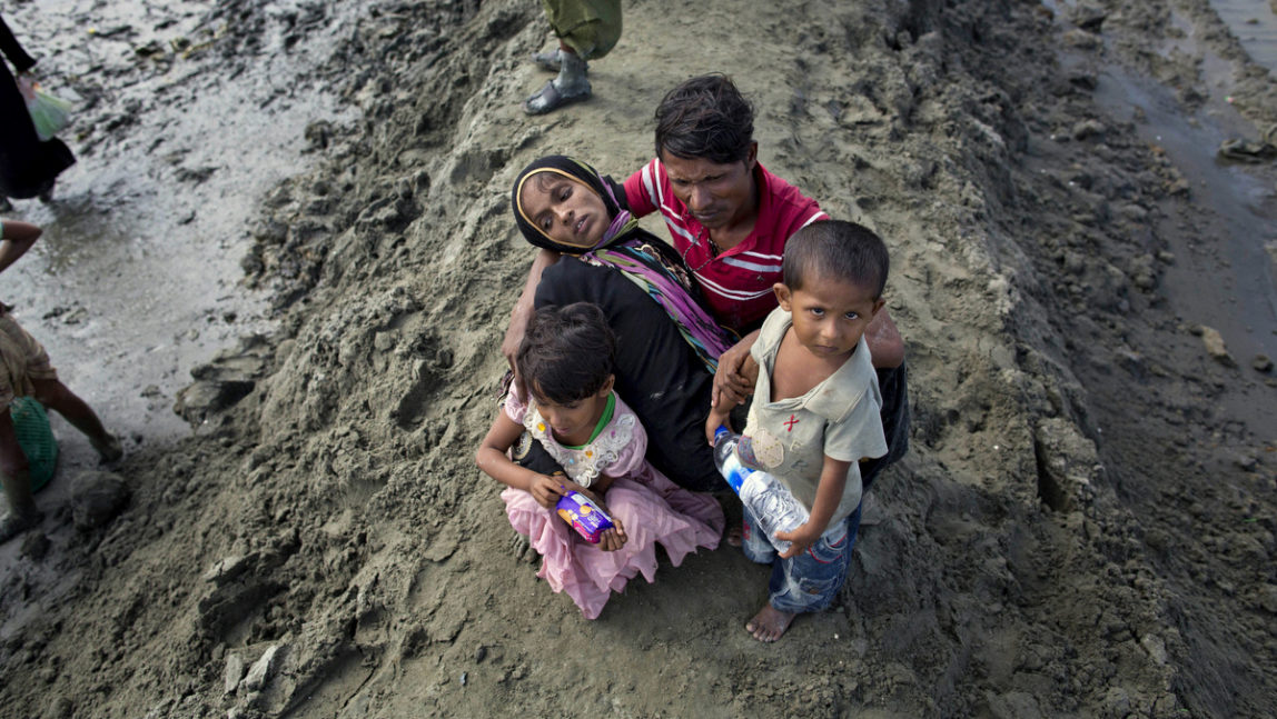 A newly arrived Rohingya Muslim Mohamed Rafiq, center, comforts his wife Noora Khatum and his children as they reach Teknaf, Bangladesh, Friday, Sept. 29, 2017. He trekked to Bangladesh as part of an exodus of a half million people from Myanmar, the largest refugee crisis to hit Asia in decades. But after climbing out of a boat on a creek on Friday, Rafiq could go no further. He collapsed onto a muddy spit of land cradling his wife in his lap, a limp figure so exhausted and so hungry she could no longer walk or even raise her wrists. (AP/Gemunu Amarasinghe)