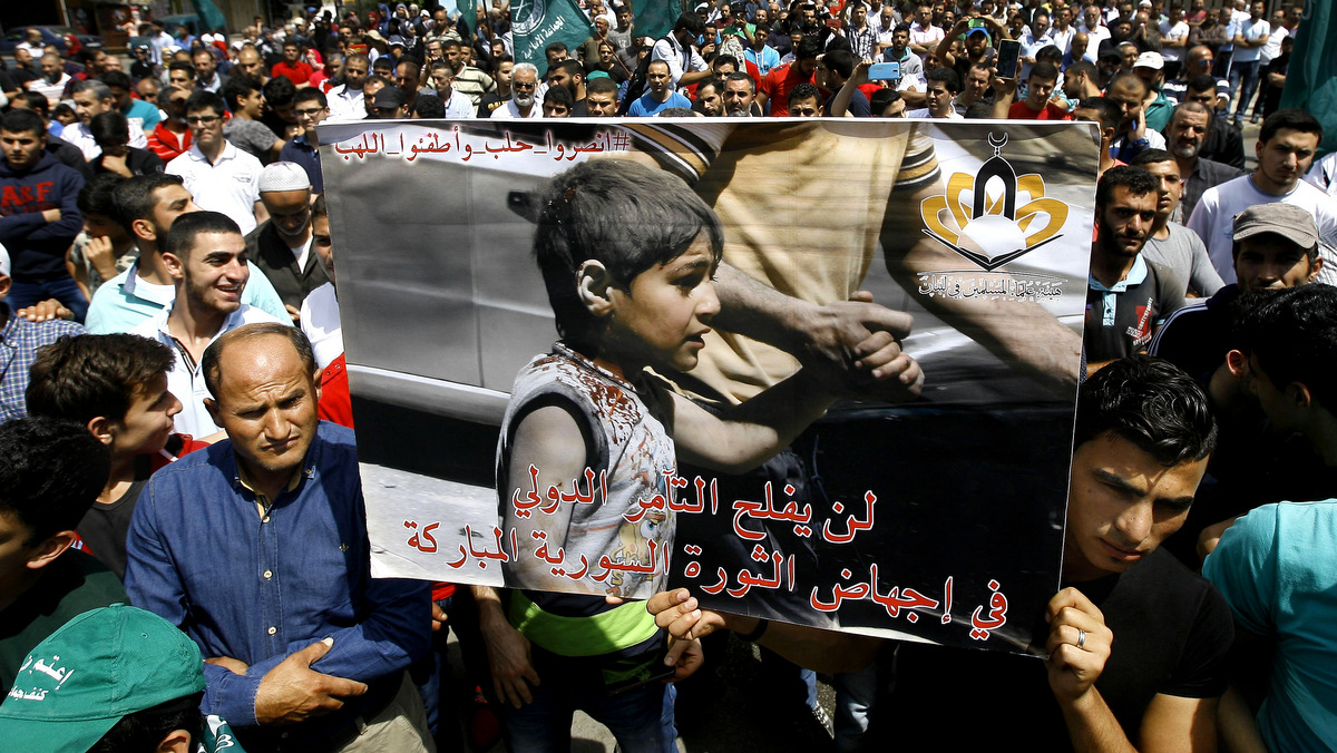 Lebanese protesters hold a placard with Arabic that reads, "the international conspiracy will not succeed in defeating the blessed Syrian revolution," during a protest against the Syrian government in Sidon, Lebanon, May 6, 2016 (AP/Mohammed Zaatari)