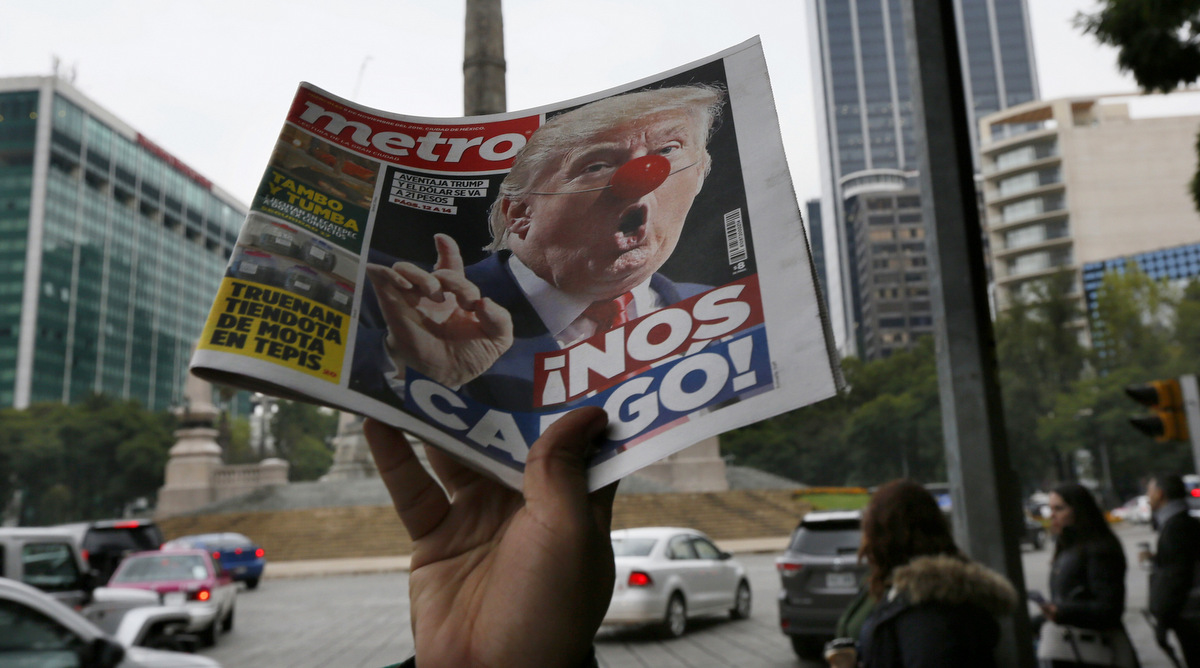 A street vendor hawks a newspaper emblazoned with an image of Donald Trump with a clown's nose, and a headline that reads in Spanish: "We're screwed!," in front of the Angel of Independence monument, in Mexico City, Wednesday, Nov. 9, 2016. (AP Photo/Marco Ugarte)