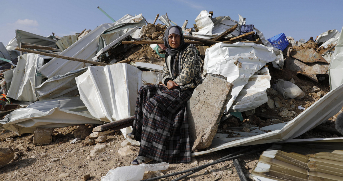 A Bedouin woman sit on the remnants of her demolished home in the Bedouin village of Umm al-Hiran, near the southern city of Beersheba, Israel, Jan. 18, 2017. (AP/Tsafrir Abayov)