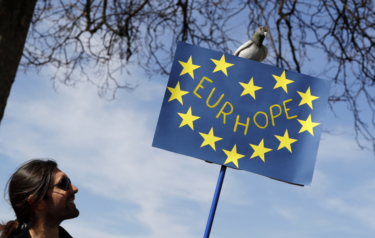 A man looks up at a model of a pigeon on top of a banner as anti Brexit campaigners gather at Hyde Park Corner in London, March 25, 2017, before they march towards Britain's parliament. (AP/Kirsty Wigglesworth)