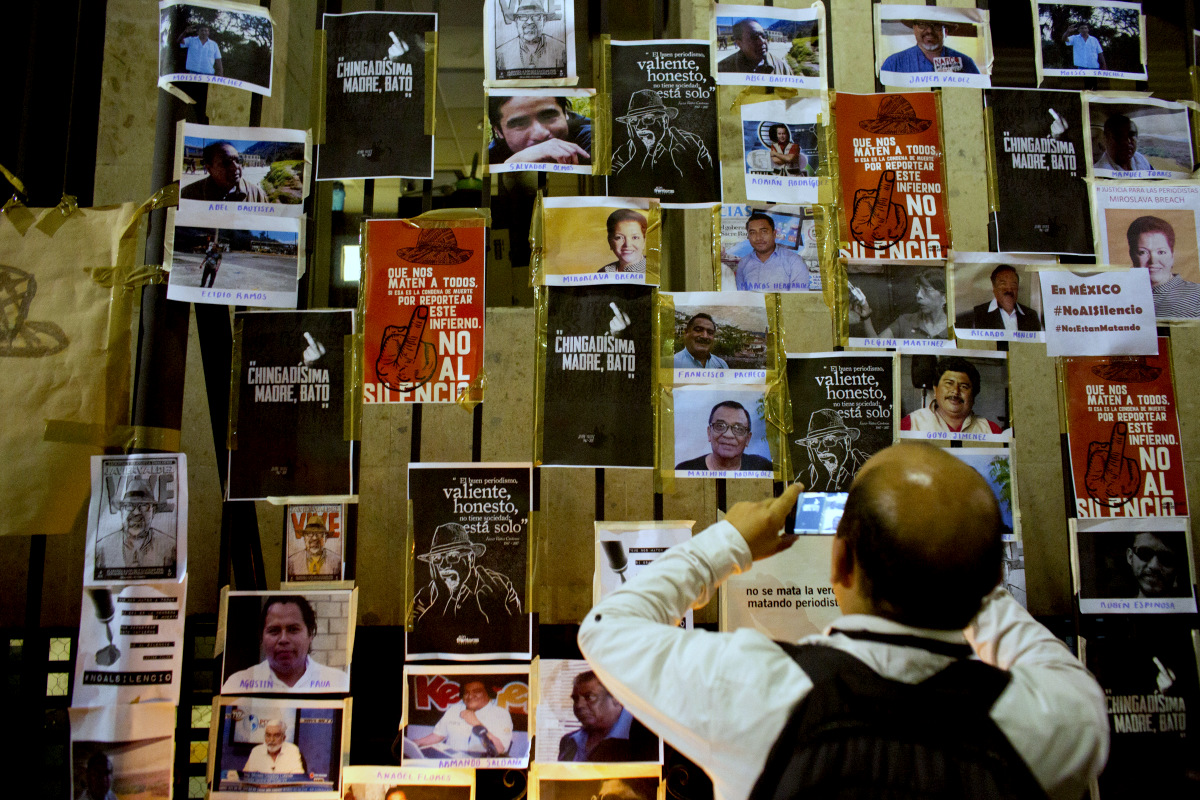 A man takes a picture of dozens of images of murdered journalists taped to a fence surrounding the Interior Ministry, during a protest against the killing of journalists, in Mexico City, May 16, 2017. Amid a Mexican government crackdown, drug trafficking and organized crime, Mexico has become one of the world's most dangerous countries for media workers. (AP/Rebecca Blackwell)
