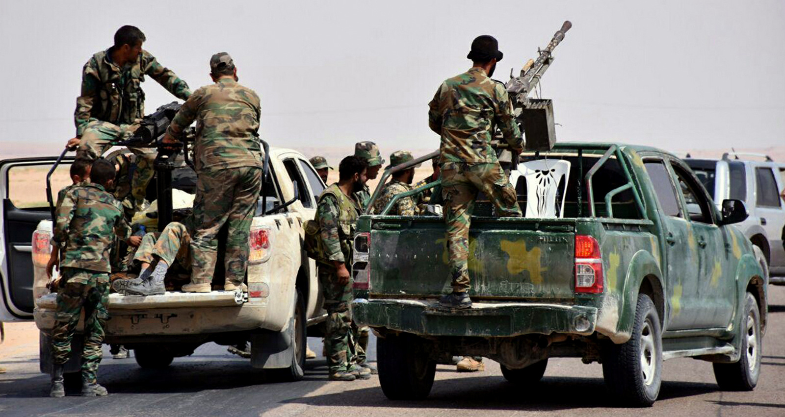 Syrian troops and pro-government gunmen standing on pickup trucks with heavy machine-guns mounted on them, in the eastern city of Deir el-Zour, Syria, Monday, Sept 4, 2017. Syrian government troops and allied forces reached the eastern city of Deir el-Zour Tuesday, breaching a nearly 3-year ISIS siege on government-held areas of the contested city near the Iraqi border. (SANA via AP)