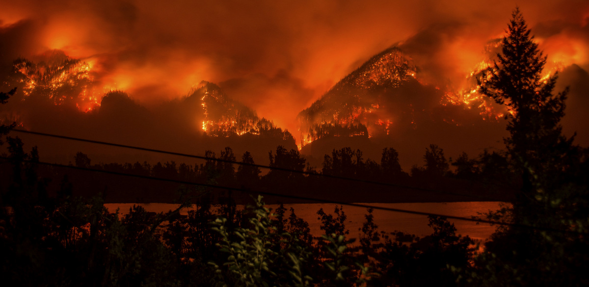A wildfire as seen from near Stevenson Wash., across the Columbia River, burning in the Columbia River Gorge above Cascade Locks, Ore. The fast-moving wildfire chewing through Oregon's Columbia River Gorge is threatening more than homes and people. It's also devouring the heart of the state's nature-loving identity. (Tristan Fortsch/KATU-TV via AP)