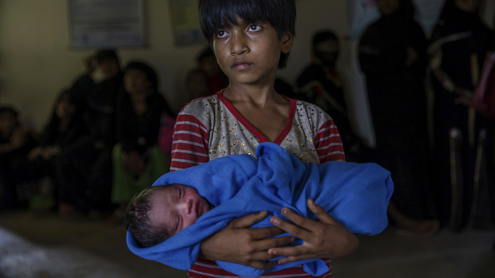 Rohingya Muslim girl Afeefa Bebi, who recently crossed over from Myanmar into Bangladesh, holds her few-hours-old brother as doctors check her mother Yasmeen Ara at a community hospital in Kutupalong refugee camp, Bangladesh, Wednesday, Sept. 13, 2017. The family crossed into Bangladesh on Sept. 3. Recent violence in Myanmar has driven hundreds of thousands of Rohingya Muslims to seek refuge across the border in Bangladesh. But Rohingya have been fleeing persecution in Buddhist-majority Myanmar for decades, and many who have made it to safety in other countries still face a precarious existence. (AP Photo/Dar Yasin)