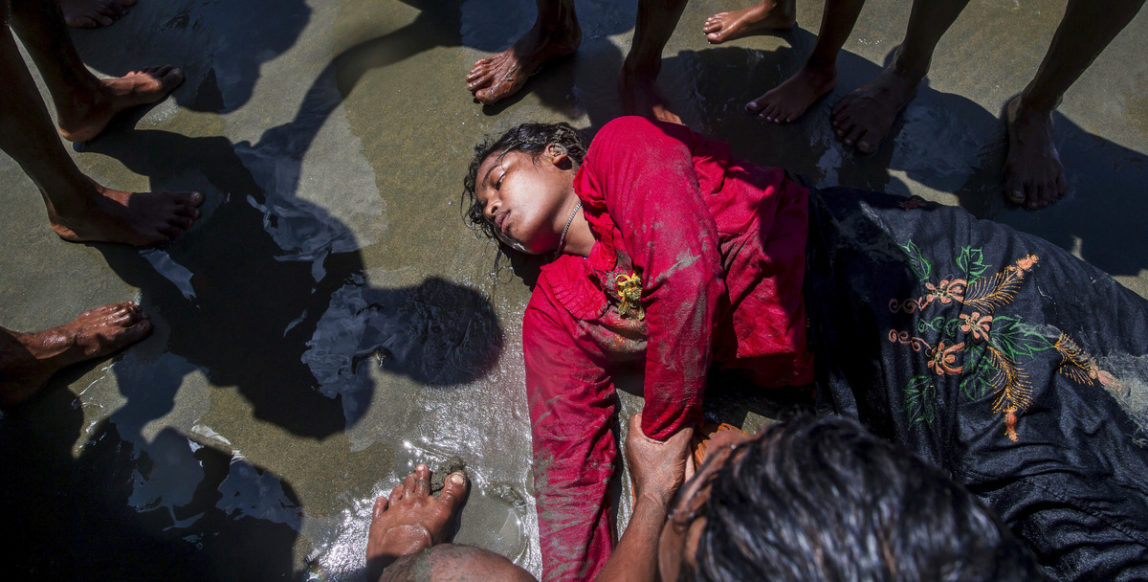 A Rohingya Muslim woman, who crossed over from Myanmar into Bangladesh, lies unconscious on the shore of the Bay of Bangal after the boat she was traveling in capsized at Shah Porir Dwip, Bangladesh, Thursday, Sept. 14, 2017. Nearly three weeks into a mass exodus of Rohingya fleeing violence in Myanmar, thousands were still flooding across the border Thursday in search of help and safety in teeming refugee settlements in Bangladesh. (AP Photo/Dar Yasin)