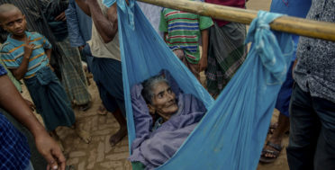 Lalmoti, an elderly Rohingya Muslim woman, lies in a sling as her son and grandson ask for direction to the hospital in Kutupalong refugee camp, Bangladesh, Monday, Sept. 18, 2017. Bangladesh has been overwhelmed with more than 400,000 Rohingya who fled their homes in the last three weeks amid a crisis the U.N. describes as ethnic cleansing. Refugee camps were already beyond capacity and new arrivals were staying in schools or huddling in makeshift settlements with no toilets along roadsides and in open fields. (AP Photo/Dar Yasin)