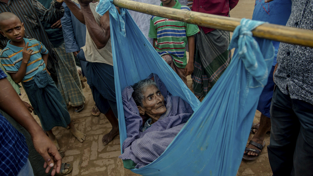 Lalmoti, an elderly Rohingya Muslim woman, lies in a sling as her son and grandson ask for direction to the hospital in Kutupalong refugee camp, Bangladesh, Monday, Sept. 18, 2017. Bangladesh has been overwhelmed with more than 400,000 Rohingya who fled their homes in the last three weeks amid a crisis the U.N. describes as ethnic cleansing. Refugee camps were already beyond capacity and new arrivals were staying in schools or huddling in makeshift settlements with no toilets along roadsides and in open fields. (AP Photo/Dar Yasin)