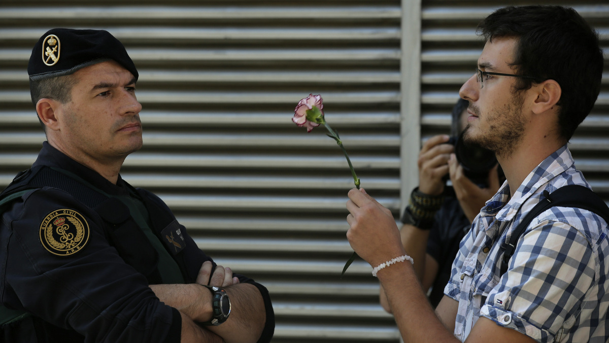 A protesters holds a carnation in front of Spanish Guardia Civil officer next to private postal service company Unipost during a protest against a search for propaganda supporting Catalonia's independence referendum in Terrassa, Spain, Tuesday, Sept. 19, 2017. The Spanish government has vowed to stop the planned Oct. 1 vote that it calls illegal. But Catalonia's leaders have pushed ahead even after Spain's Constitutional Court suspended the law passed by Catalonia's regional parliament that convoked the referendum. A protesters holds a carnation in front of Spanish Guardia Civil officer next to private postal service company Unipost during a protest against a search for propaganda supporting Catalonia's independence referendum in Terrassa, Spain, Tuesday, Sept. 19, 2017. The Spanish government has vowed to stop the planned Oct. 1 vote that it calls illegal. But Catalonia's leaders have pushed ahead even after Spain's Constitutional Court suspended the law passed by Catalonia's regional parliament that convoked the referendum. (AP/Manu Fernandez)(AP/Manu Fernandez)