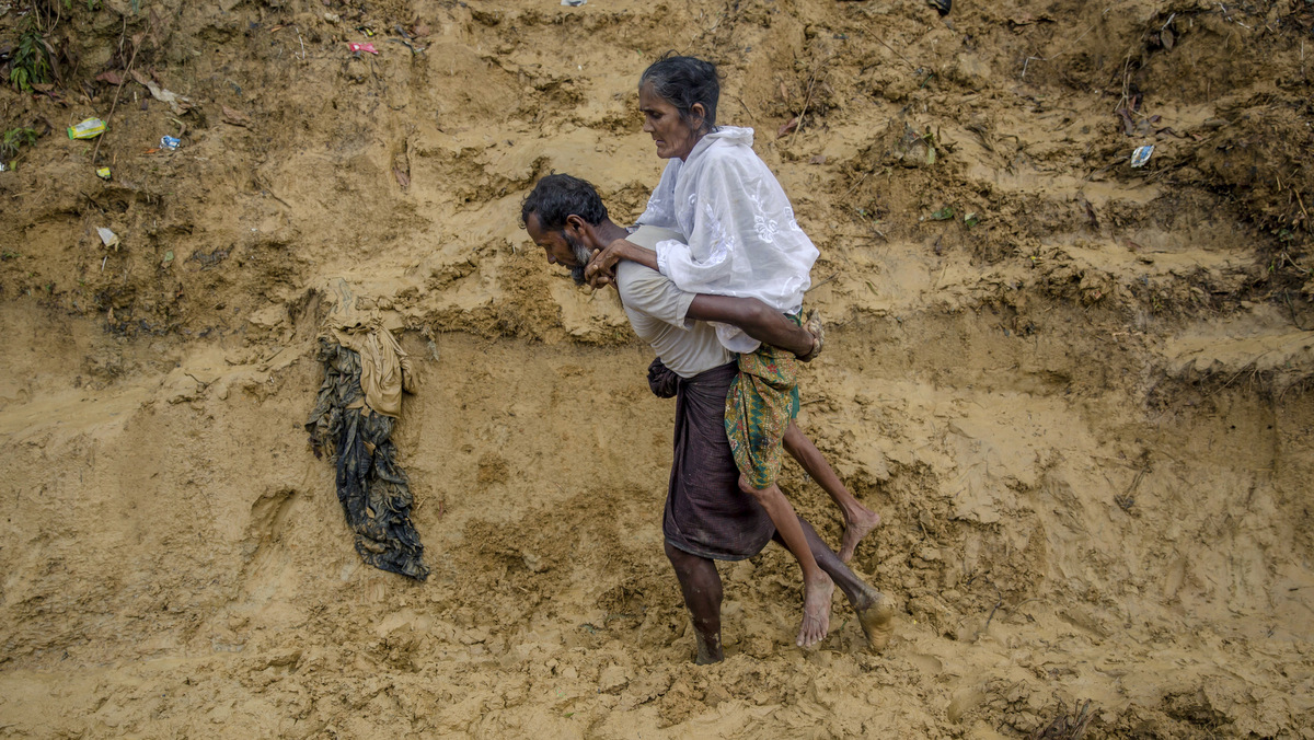 Alishaan, a Rohingya Muslim man, walks towards a hospital carrying his sick mother Aishya Khatoon at Taiy Khali refugee camp, Bangladesh, Thursday, Sept. 21, 2017. More than 400,000 Rohingya Muslims have fled to Bangladesh since Aug. 25. (AP/Dar Yasin)